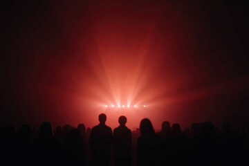 Fototapeta premium Silhouettes of people against vibrant red lights create an immer