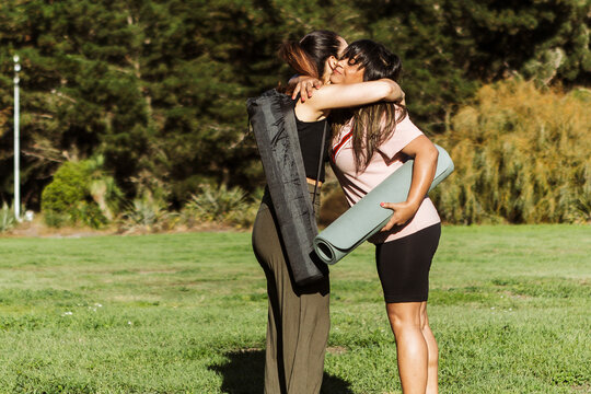 Women embracing with yoga mats outdoors in autumn