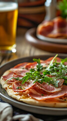 Fresh pizza topped with ham and arugula served with beer  