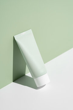Minimalist cosmetic tube on pastel green background