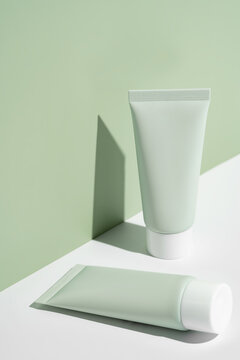 Minimalist cosmetic packaging on sage green background