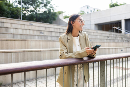 Businesswoman in casual setting holding smartphone