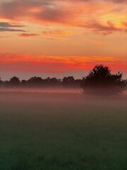 Fototapeta premium fantastic orange and purple sky, foggy sunset at the field in the countryside
