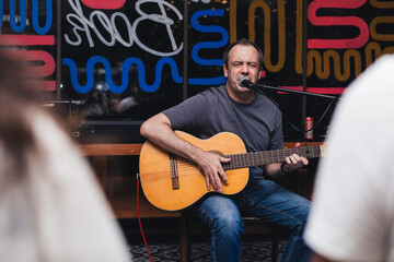 Man performing live music with acoustic guitar in cafe