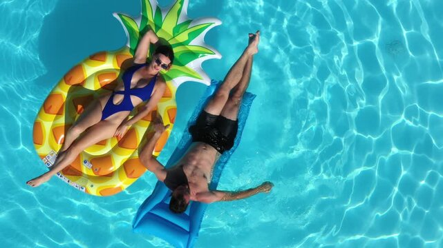 A joyful young couple unwinding in a swimming pool, sharing smiles and enjoying the moment. Concept vacation, travel, and relaxation.