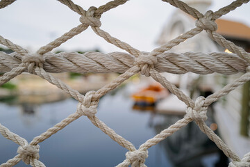 A fence made of rope at a W. Dennis Cape Cod Pond with a sailboat in the background