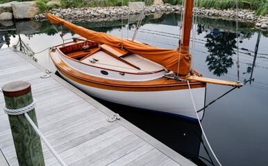 Beautiful restored wood sailboat sits at a small dock on Cape Cod