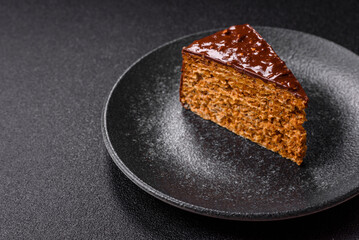 A slice of sweet layered cake covered in chocolate with nuts and caramel. A slice of chocolate cake