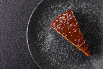 A slice of sweet layered cake covered in chocolate with nuts and caramel. A slice of chocolate cake