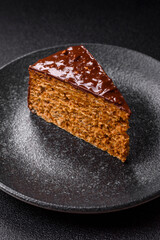 A slice of sweet layered cake covered in chocolate with nuts and caramel. A slice of chocolate cake