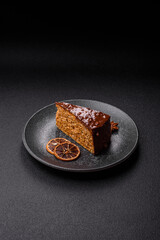 A slice of sweet layered cake covered in chocolate with nuts and caramel. A slice of chocolate cake