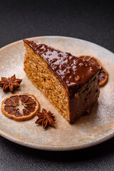 A slice of sweet layered cake covered in chocolate with nuts and caramel. A slice of chocolate cake