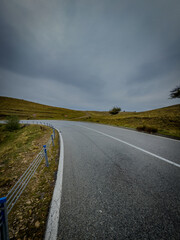 Curved mountain road beneath dramatic sky