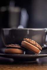Sweet chocolate pralines. Chocolate candies and coffee cup on wooden table.