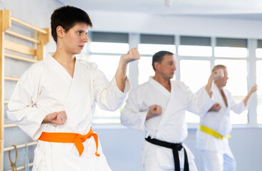Fototapeta premium Fighting stance of men of different ages during group karate training. Young guy trains punches