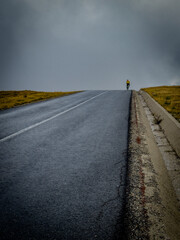 Cyclist climbs steep empty road into clouds