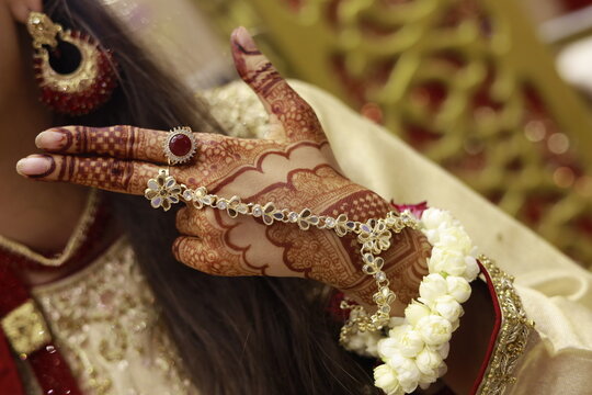 Bridal Hand Detail: Henna Mehndi, Floral Bracelet, Gold Hath Phool Jewelry, and Earrings