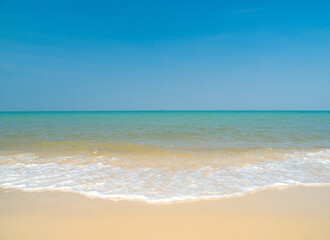 Peaceful tropical sea beach with gentle waves rolling onto golden sand under bright blue sky with fluffy white clouds. relaxing summer scene perfect scene for travel holliday and nature lovers