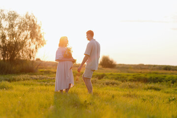 Couple holding hands in a sunlit field, sharing a tender moment together during sunset