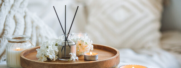 Banner. Comfortable atmosphere, spring delicious fresh smell. Aroma diffuser, burning candle, blooming hyacinth flowers and perfume on wooden bamboo tray. Cozy home decor, hygge, aromatherapy concept