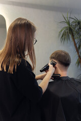 Professional woman barber wielding electric hair clipper making Fashionable haircut. Bearded Man client visit gentleman grooming beauty salon for hairstyle care. Modern Haircut style in barber shop