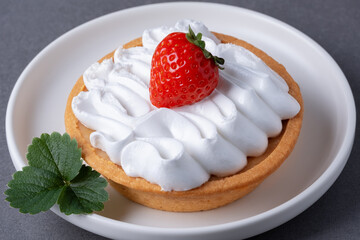 Delicious strawberry tart topped with whipped cream served on a white plate