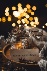 Home aromatherapy. Aroma candles with pine extract, spruce cone, cinnamon, anise, vanilla scent, candles, wooden table. Cozy atmosphere, winter inspiration, knitted sweater. Merry Christmas note