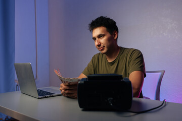 Cashier counting Russian banknotes while working at desk with laptop and money counter machine, illustrating financial accounting in modern office environment. Concept of illegal cash withdrawal