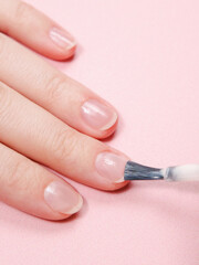 woman paints her nails with nail polish and applies nail polish with a brush. nail and hand skin care, nail service salon, manicure and pedicure.