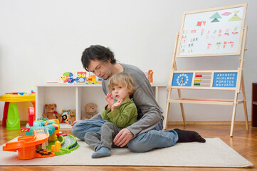 Father and sweet little child boy having fun playing with cars and colorful toys, on the floor, at home. Beautiful family moment, indoors