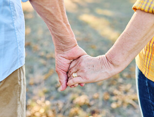 Happy active senior couple having fun talking holding hands and bonding in park outdoors