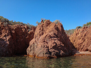 Red Rocky Cliffs Rising Above Clear Coastal Waters