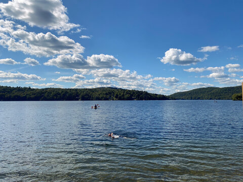 Lake with Swimmer and Kayaks under Blue Sky