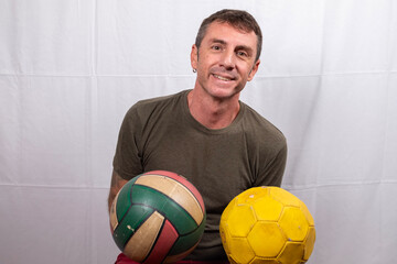 Man portrayed with two sports balls in his hands. The man is forty years old, of Caucasian origin...