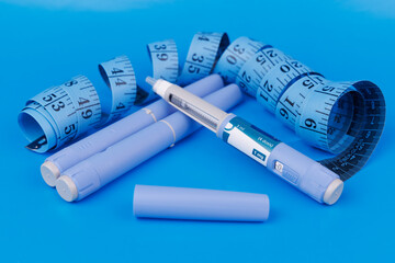 Healthcare composition showing semaglutide pens with white pill bottles, blue tapes, and vitamin B12 glass ampoules on blue background.