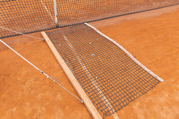 Tennis net and clay court detail. The image illustrates the concept of sports infrastructure, game preparation, and precision in maintaining court equipment.