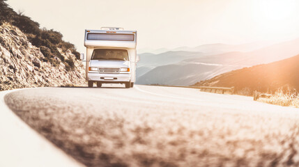 A white camper van approaches head-on while driving a curved mountain road at sunset, with scenic hills and soft light creating a travel adventure mood.