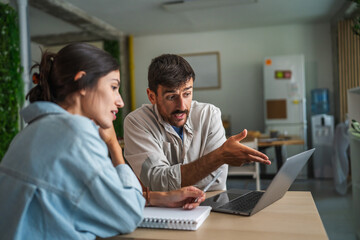 Collaborating couple working on laptop in modern office