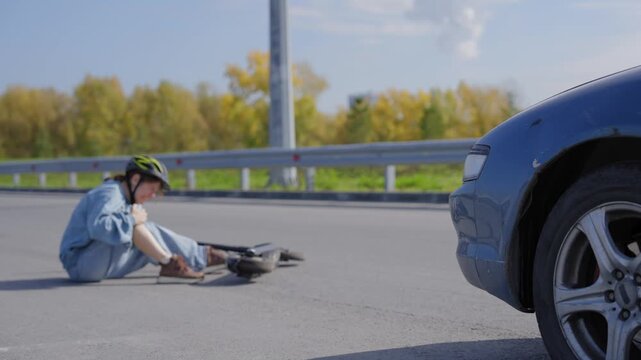 A Caucasian woman on a scooter after being hit by a car.