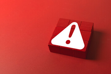 A red warning sign with an exclamation mark on wooden blocks. A concept for danger, risk, errors, and critical alerts. A symbol for a hazard or an emergency that needs attention.