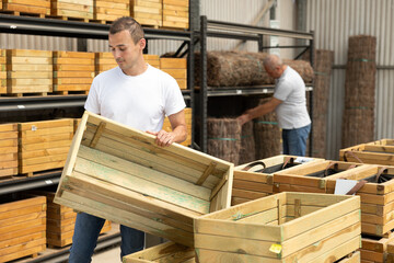 Young man shopper choosing wooden box in gardening department of hardware store