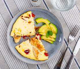 Appetizing chicken omelet with fresh sliced avocado served on plate for breakfast