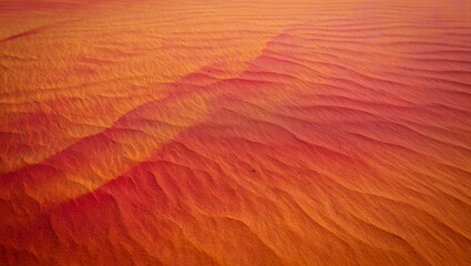 Obraz premium Sunlit desert sand dune with sharp wind etched ripples and smooth flowing patterns in vivid orange red tones, full frame texture evoking arid, warm landscapes and erosion