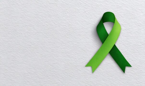 Green ribbon on textured white paper symbolizing mental health awareness and support