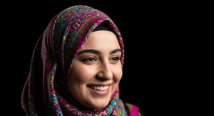 Portrait of a smiling woman wearing colorful patterned hijab with isolated black background