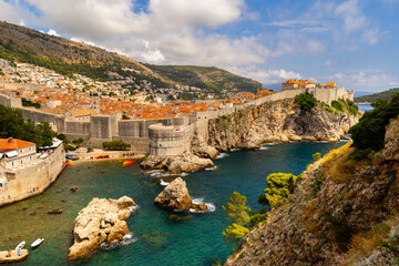 Vivid contrast of blue sky and red tiled roofs is hallmark of Dubrovnik Fortress. Small ancient city fits inside defensive structures and resembles harsh medieval times..