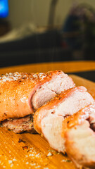 Freshly sliced roasted pork revealing juicy, tender meat inside. Half the roast remains whole with gorgeous golden crackling, while beautiful succulent slices lay beside it on a wooden board.