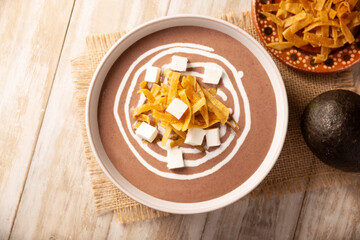 Creamy bean soup. In Mexico known as Crema de Frijoles, nutritious homemade food recipe, commonly accompanied with cheese, cream, avocado and corn tortilla cut into strips and fried.