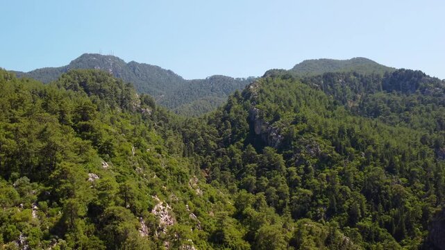 aerial drone footage captures the natural beauty of the mountainous and heavily forested landscape near Turunc, a picturesque resort town in the Marmaris district of Mugla Province, Turkey. The vibran