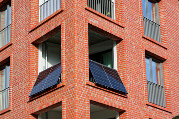 Wide balcony on red brick facade fitted with solar panels shows a german balcony power plant